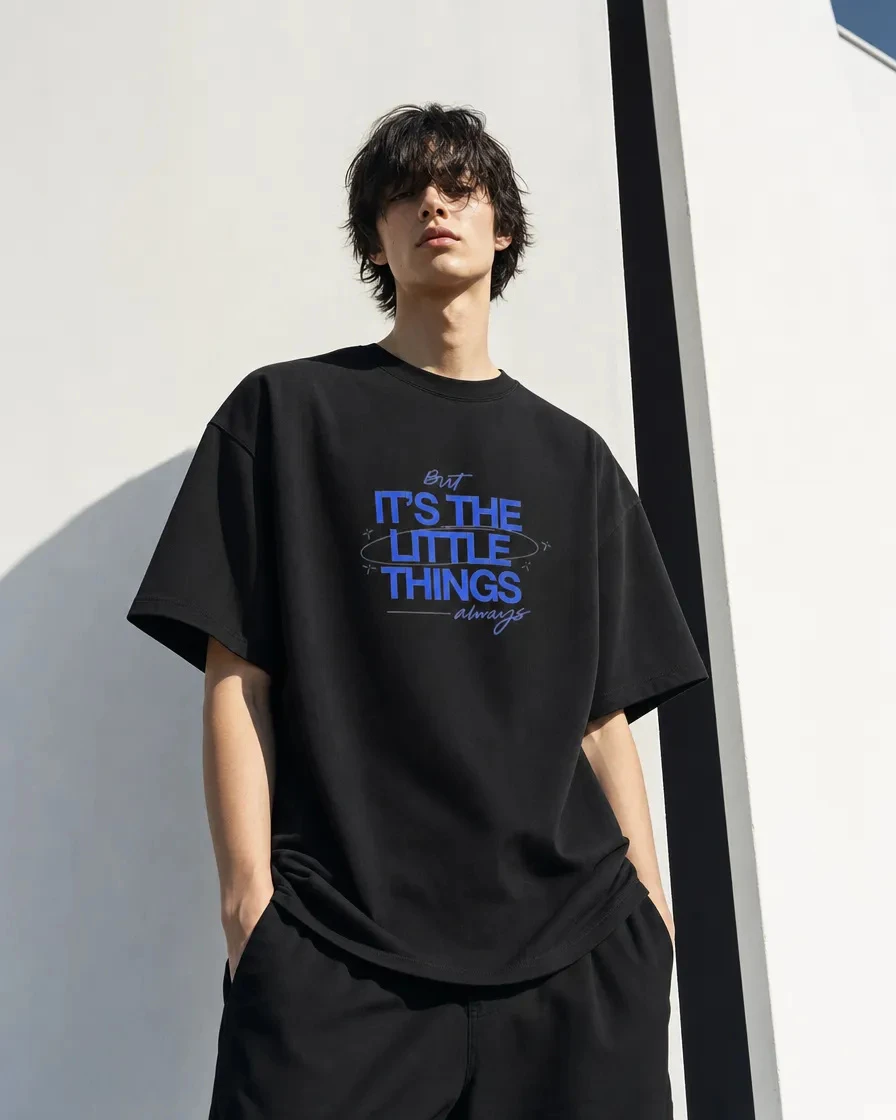 Androgynous model wearing the black oversized North Wear T-shirt with its blue chest graphic in an optical-white architectural setting
