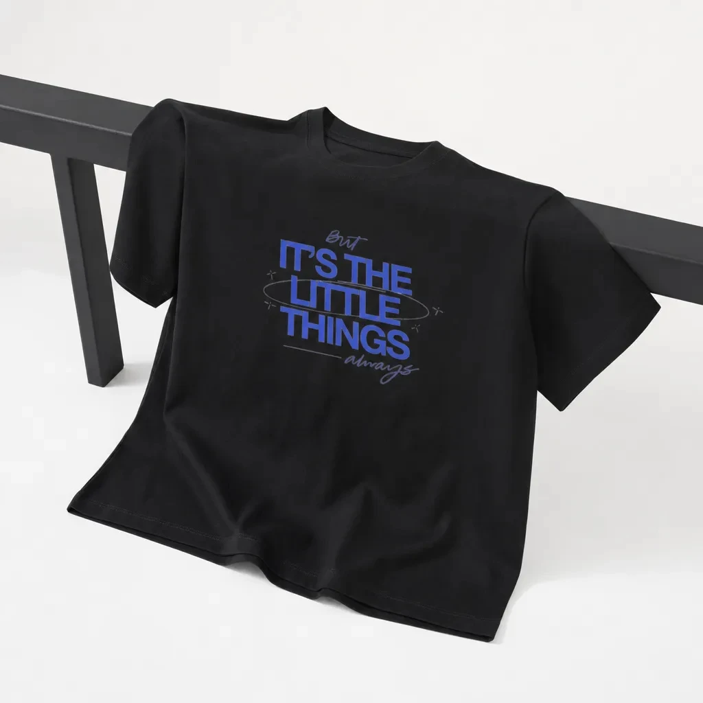 The exact black oversized T-shirt draped over a low charcoal rail in an optical-white studio