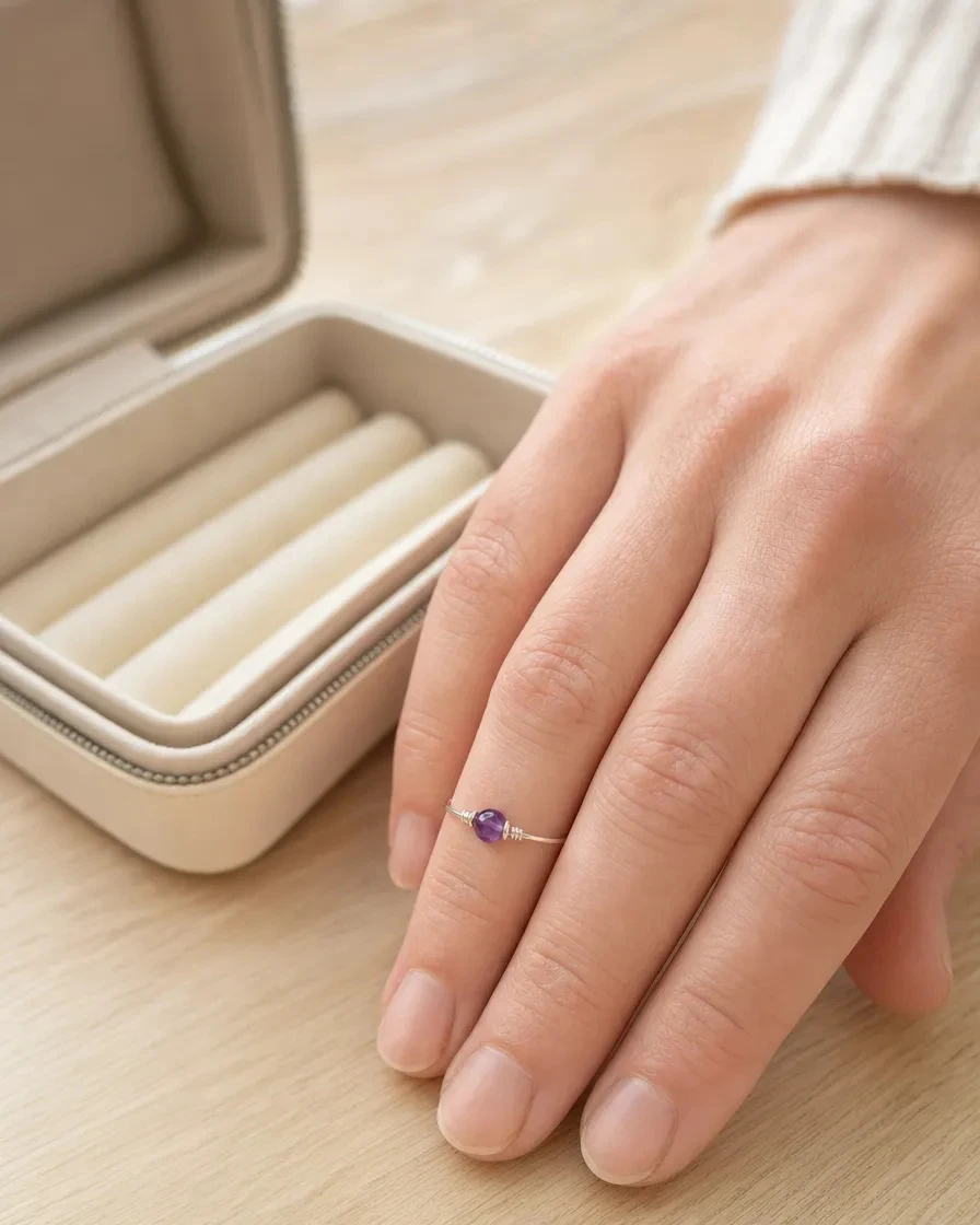 Amethyst Ring worn on a relaxed hand beside an open cream keepsake folio