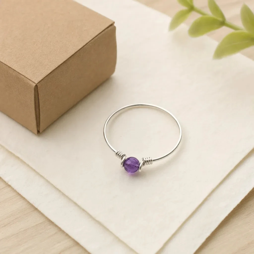 Sterling Silver Amethyst Ring beside its tiny craft paper gift box on folded parchment
